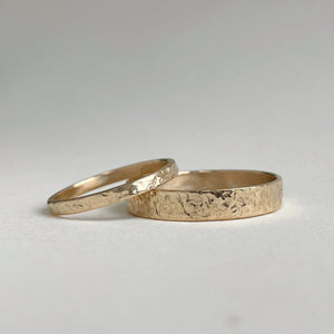 Image of a handcrafted thin 2mm hammered finish yellow gold wedding band with a freestyle hammered texture. The band is ethically sourced and made using recycled 10kt, 14kt, or 18kt yellow gold. The band is stamped with its karat weight and hallmarked. Available in various sizes and made to order, shipping includes tracking within Canada and the United States, and internationally