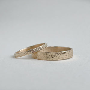 Image of a 4mm hammered finish yellow gold wedding band with a freestyle hammered texture. The band is made with recycled ethical solid 10kt, 14kt, or 18kt yellow gold and is stamped with its karat weight and hallmarked. Available in a range of sizes and made to order, shipping includes tracking within Canada and the United States, and internationally. The ring comes gift-wrapped, making it a special and meaningful present