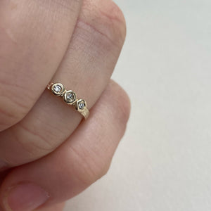 Image of a thin 10k, 14kt, or 18kt yellow gold wedding band with three 1.5mm round Canadian diamonds. The diamonds are SI2-SI3 melee analyzed by GIA. The band is ethically sourced and made from recycled gold.