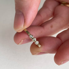Load image into Gallery viewer, Image of a thin 10k, 14kt, or 18kt yellow gold wedding band with three 1.5mm round Canadian diamonds. The diamonds are SI2-SI3 melee analyzed by GIA. The band is ethically sourced and made from recycled gold.