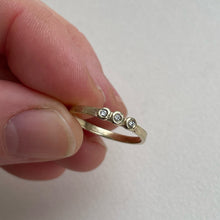 Load image into Gallery viewer, Image of a thin 10k, 14kt, or 18kt yellow gold wedding band with three 1.5mm round Canadian diamonds. The diamonds are SI2-SI3 melee analyzed by GIA. The band is ethically sourced and made from recycled gold.