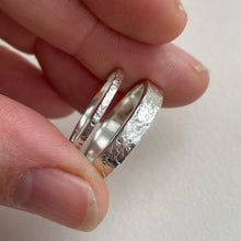 Load image into Gallery viewer, Textured hammered Sterling Silver wedding band with a rustic and unique design, available in a range of sizes, and gift-wrapped. Measures 4mm in width and 1.25mm in thickness. Perfect as a sustainable and eco-friendly wedding band with a personal touch.