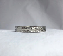 Load image into Gallery viewer, A close-up photo of a white gold wedding band with a geometric-inspired design, handcrafted using ethically sourced and recycled gold. The band measures 4mm wide and 1mm thick and is available in various sizes
