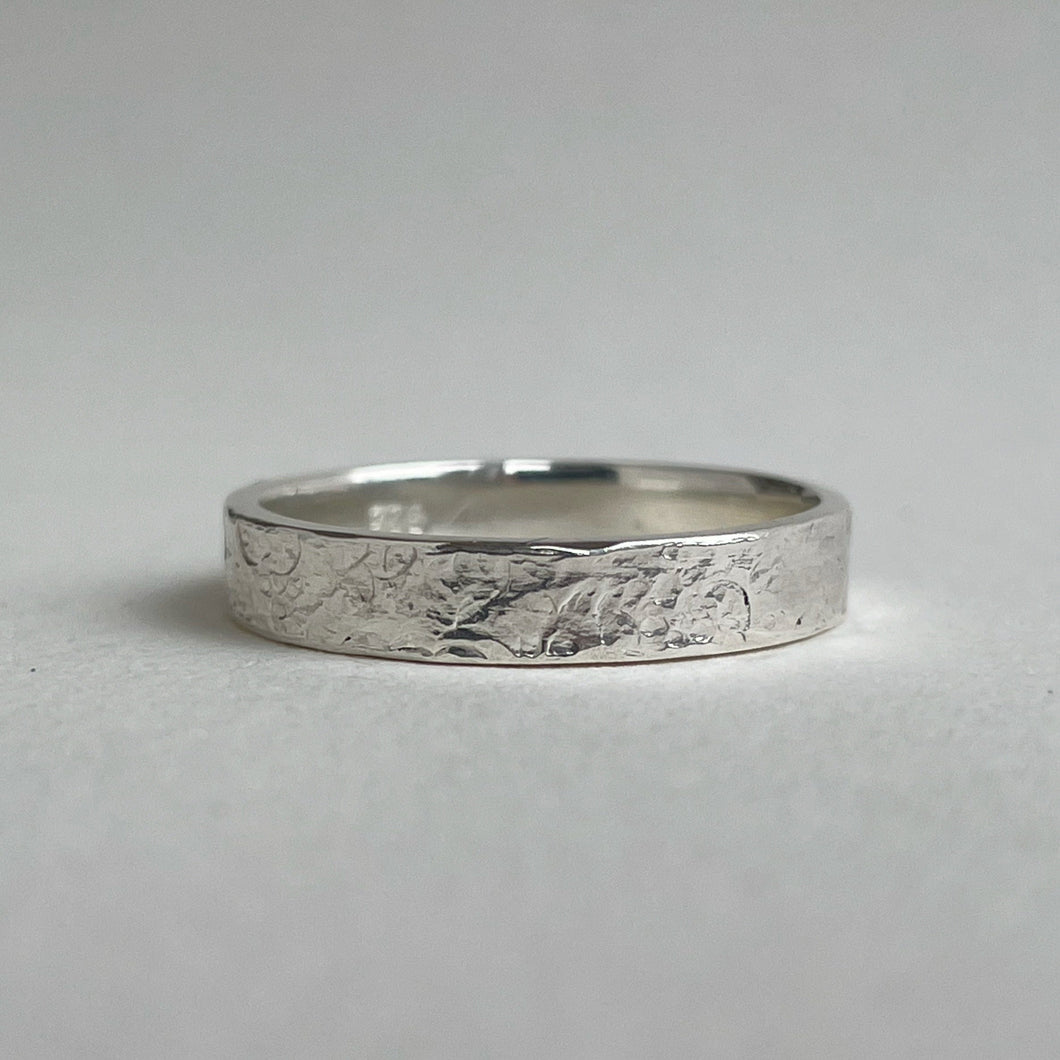 Textured hammered Sterling Silver wedding band with a rustic and unique design, available in a range of sizes, and gift-wrapped. Measures 4mm in width and 1.25mm in thickness. Perfect as a sustainable and eco-friendly wedding band with a personal touch.