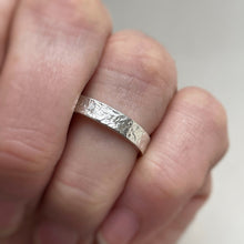 Load image into Gallery viewer, Textured hammered Sterling Silver wedding band with a rustic and unique design, available in a range of sizes, and gift-wrapped. Measures 4mm in width and 1.25mm in thickness. Perfect as a sustainable and eco-friendly wedding band with a personal touch.
