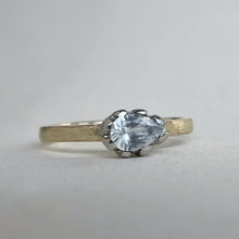 Load image into Gallery viewer, Pear shaped solitaire featuring a 6x4mm AA white sapphire. The band is yellow gold with a white gold setting.  A rustic texture is applied.
