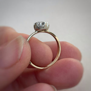 Pear shaped solitaire featuring a 6x4mm AA white sapphire. The band is yellow gold with a white gold setting. A rustic texture is applied.