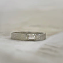Load image into Gallery viewer, Solitaire baguette engagement ring with rustic texture, handcrafted in eco-friendly 10k white gold and ethically sourced white sapphire.
