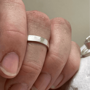 Brushed hammered wedding ring on a hand