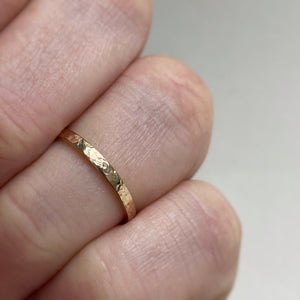 Image of a handcrafted thin 2mm hammered finish yellow gold wedding band with a freestyle hammered texture. The band is ethically sourced and made using recycled 10kt, 14kt, or 18kt yellow gold. The band is stamped with its karat weight and hallmarked. Available in various sizes and made to order, shipping includes tracking within Canada and the United States, and internationally
