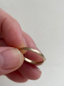 Handcrafted thin hammered brushed finish yellow gold wedding band with a freestyle hammered texture